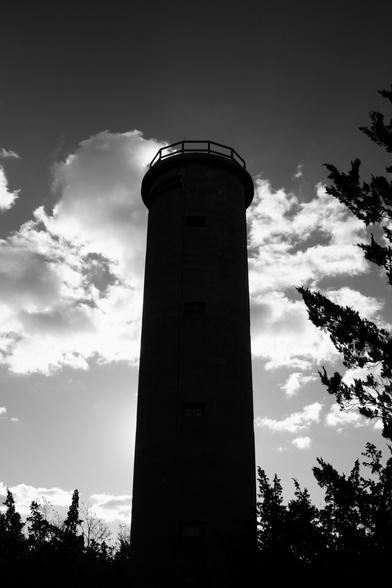 Monochrome image of a cement tower, black in shadow, illuminated from behind by the sun.