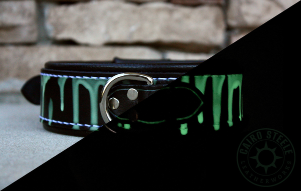 A black leather collar with pale green paint drips that glow bright green in the dark