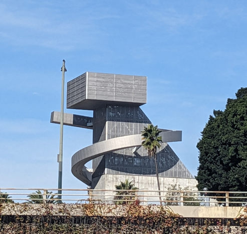 Large sculpture that looks like twisted wire around blocks. There's a palm tree for scale