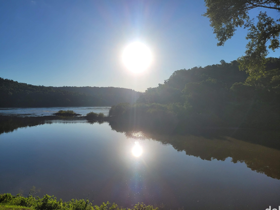 Encontro do Rio Peperi, que vem da direita (norte) com o Rio Uruguai que vem da esquerda (leste) e prossegue em frente. As margens vistas adiante são matas fechadas. Foto com o sol ao centro em um fim de tarde, ou seja, diretamente em sentido oeste.
