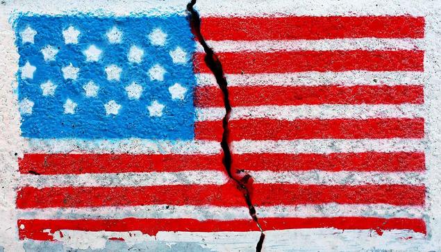 An American flag, painted on a white wall, with a crack running through it.