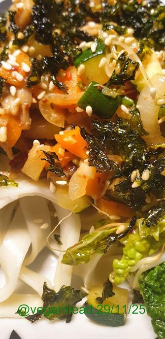 A close up view of the Thai style Stir Fried Vegetables (Carrot, Courgette, Red Pepper, White Onion, Savoy Cabbage, Sprouted Fenugreek Seeds, Fresh Ginger, Garlic & Lemongrass, Dried Chilli Flakes) & 'OUMPH!' Herb & Garlic Chunks served on Udon noodles. Topped w/ toasted sesame seeds & toasted seaweed.