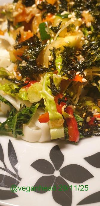 A close up view of the Thai style Stir Fried Vegetables (Carrot, Courgette, Red Pepper, White Onion, Savoy Cabbage, Sprouted Fenugreek Seeds, Fresh Ginger, Garlic & Lemongrass, Dried Chilli Flakes) & 'OUMPH!' Herb & Garlic Chunks served on Udon noodles. Topped w/ toasted sesame seeds & toasted seaweed.
