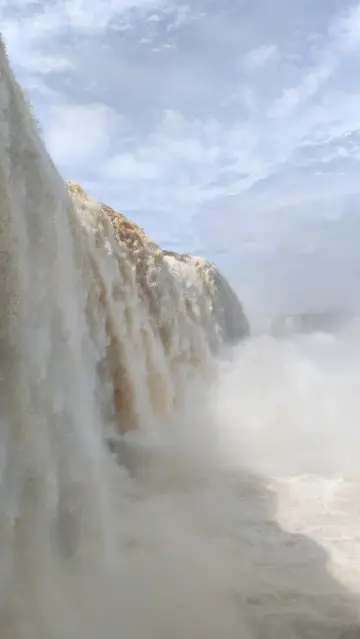 Foto de uma das maiores quedas das Cataratas do Iguaçu, a queda d'água está bem próximo e tudo que é possível ver é água, névoa da queda e o céu acima bem nublado.