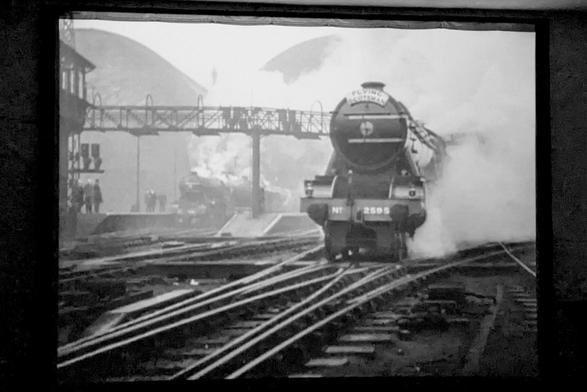 Front of a steam locomotive with steam billowing and tracks in front