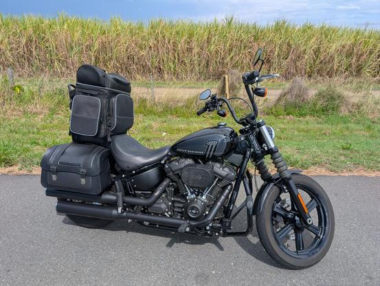 Photo of a black Harley-Davidson with saddlebags, and a big luggage bag strapped over the pillion (passenger) seat.