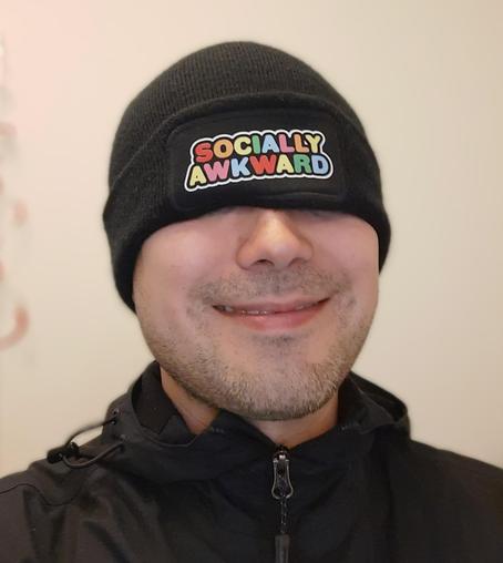 A photo of me wearing a beanie hat that has the words "Socially Awkward" on the front. I have pulled it low, so it covers my eyes