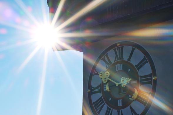 Ziffernblatt des Uhrturms rechts. Links der Sonnenstern der Sonne, welcher den Uhrturm überstrahlt