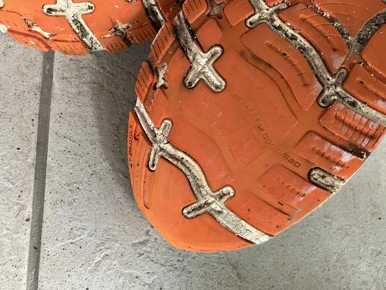 Orangene Sohle eines Sportschuhs, die an der Spitze kein Profil mehr hat.