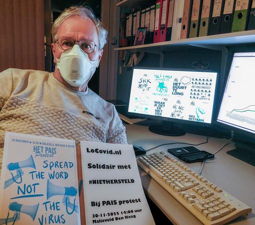 Selfie op mijn zolderkamer bij de pc, met op het scherm posters van de protestactie #PAISProtest van #NietHersteld. Zelf draag ik een FFP2 masker en heb een bord voor mijn buik met een van de protestposters, en de tekst: locovid.nl Solidair met #NIETHERSTELD Bij PAIS protest 30-11-2025 14:00 uur Malieveld Den Haag