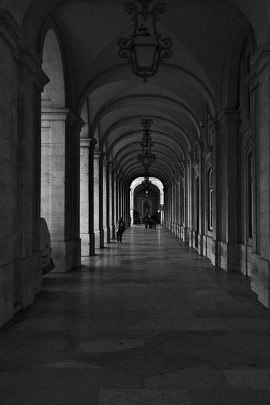 BW picture of an empty area covered by arches that surrounds the main square.