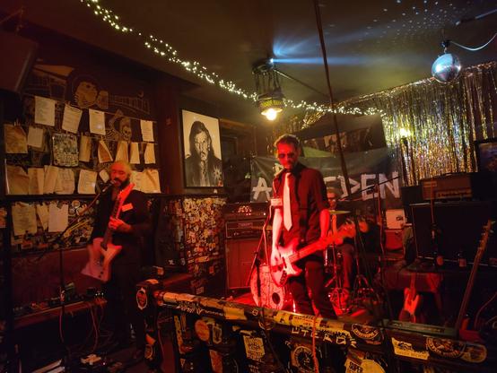 die Band Die Leistungsträger. im Franken. im Hintergrund ist ein riesiges poträt von Lemmy