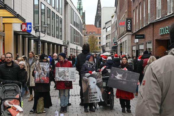 Aktivis stehen in der Innenstadt und halten Schilder mit Tieren darauf und Sprüchen wie "Kein Lammbraten" die Stadt ist sehr voll.