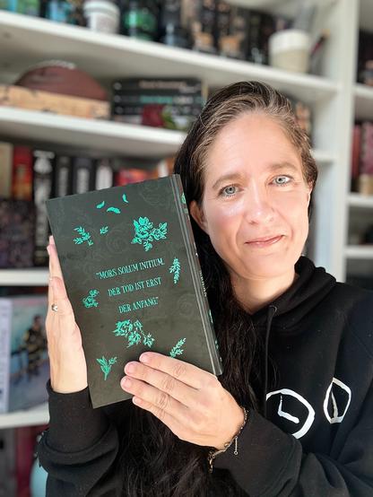 Ich halte folgendes Buch vor meinem Bücherregal in meinen Händen:

Vicious Secret
aus der Reihe Obsidian Order
von Morgan Bridges
vom Verlag Penguin Random House

Ich zeige die Rückseite. Sie ist dunkelgrau mit grüner Schrift. Darauf steht:

»MORS SOLUM INITIUM.
DER TOD IST ERST DER ANFANG.«