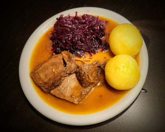 Ein Teller mit Seidenklößen (Kartoffeln), Rotkohl und westfälischem Sauerbraten (Rind + keine Rosinen) mit viieeeeeel Soße (gezogen aus dem Sud mit Wacholderbeeren, Senfsaat, Essig etc. und angereichert mit Karotten, Zwiebeln und Rübenkraut für die süße Note)