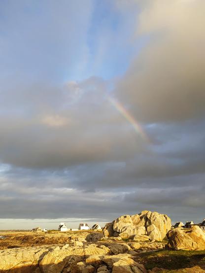 Arc en ciel dans les nuages, au-dessus des rochers dorés par le soleil à St Guénolé