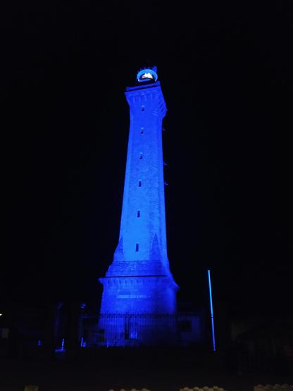Phare d'Eckmühl éclairé en bleu se détachant sur le noir de la nuit