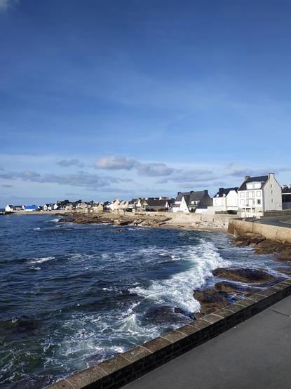 Vagues blanches sur l'océan, des maisons blanches en arrière plan