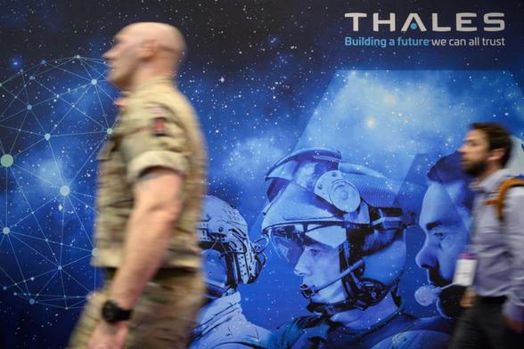 Unos viistantes junto a un cartel de Thales durante el primer día de la feria Defence and Security Equipment International, el 14 de septiembre de 2021, en Londres. (Leon Neal / Getty Images)