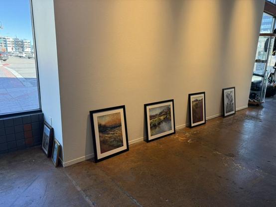 Framed paintings leaning against white walls.