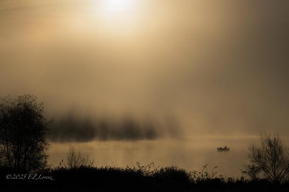 Foggy morning at a lake with a fishing boat