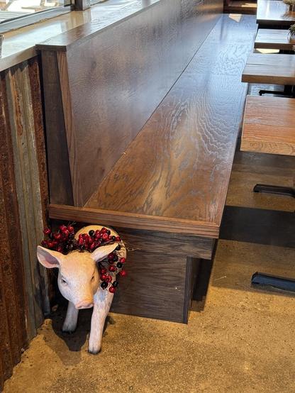 One end of the bench has the front half of a pig with a garland of red berries around its neck.