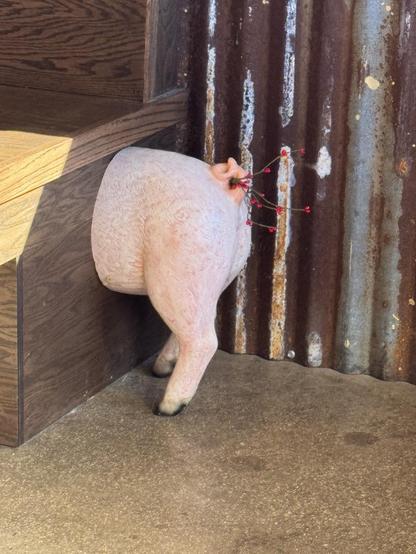 Oh, how to describe this end? The back end of the pig sticking out the other end of the bench has branches and small red flowers that appear to match the ones around the front end of the pig.