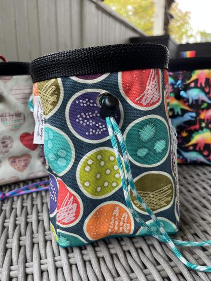 A chalk bag with a teal background and a bright pattern of Petri dishes.