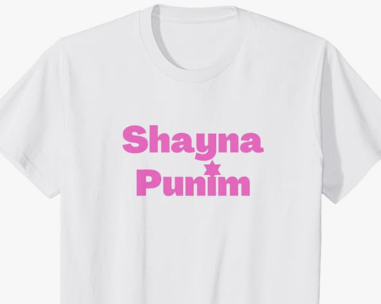The Yiddish Shayna Punim is shown in pink lettering on a T shirt.