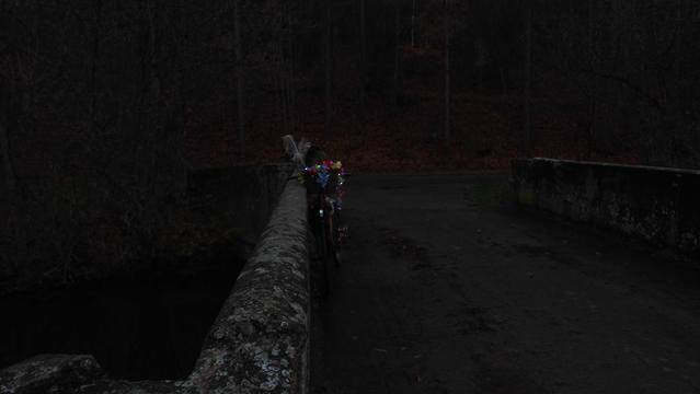 Fahrrad mit Lichterkette an eine Brückengeländer gelehnt. Es ist sehr dämmrig