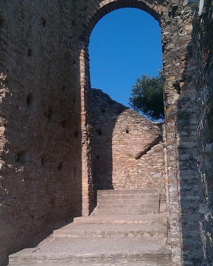 Eine Treppe führt hoch zu einem Torbogen der sehr hoch und schmal ist.