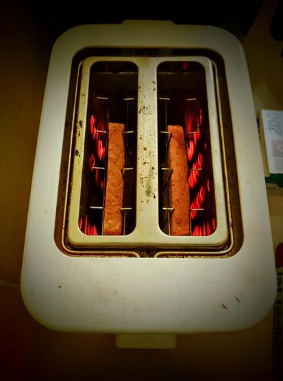 Filaments glow red as toast toasts in the toaster, round side down.