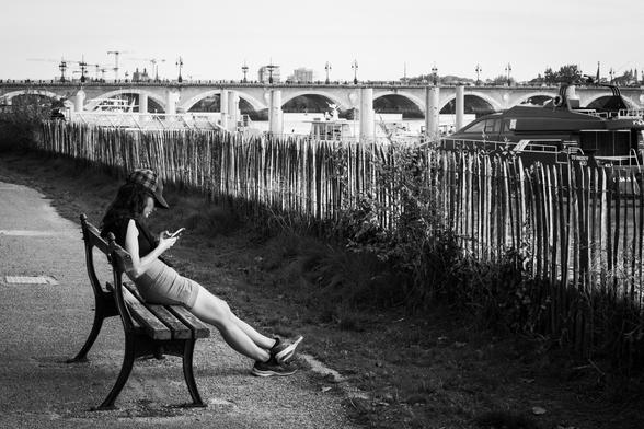 Path along the docks with a person sitting on a bench aligned with the perspective
