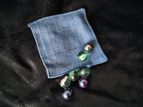 Un carré de tissus cousu avec des billes devant. on voit qu'il y a une bille a l'intérieur du carré de tissus