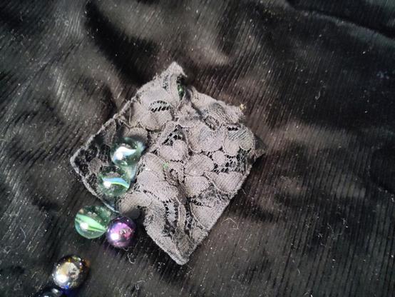 Un carré de dentelle noire avec des billes devant. On voit qu'il y a des billes a l'intérieur du carré de dentelle