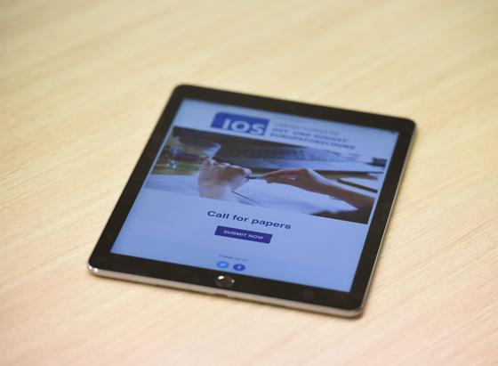 Tablet displaying the IOS Leibniz Institute website with "Call for papers" announcement and "SUBMIT NOW" button on a wooden surface.