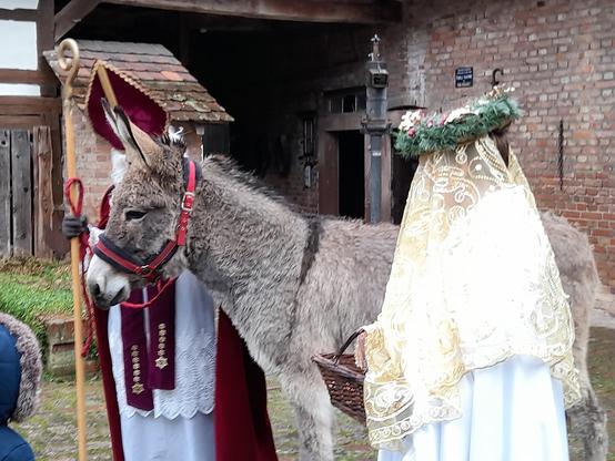 In front of the outhouse (historical, museum) and the manure pump, a very kind grey donkey looks at a child (not visible), St. Nicolas and Chrischtkindl beside.
Yes, of course I stroked the donkey and spoke to the nice grey lady. Like most of the children.