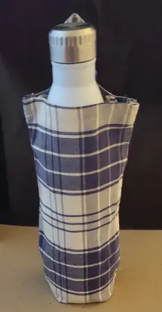 Étui en tissu blanc à carreaux bleus dans lequel il y a une gourde blanche dont le goulot gris argent dépasse. Le tout sur fond noir.