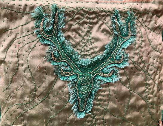 Closeup image of the stag embroidered onto green fabric.