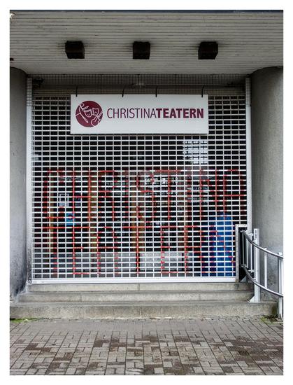 En stående bild på ett galler framför ingången till en teater som enligt skylten och texten i rött på gallret heter Christinateatern.