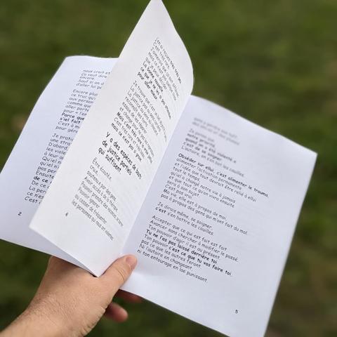 le fanzine tenu en main, ouvert. les feuilles volent au vent, le texte n'est pas lisible.