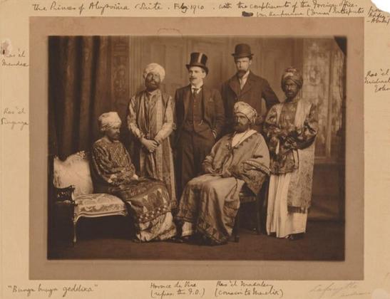 © National Portrait Gallery, London
The Dreadnought Hoax was a notorious practical joke in British military history. The hoax was orchestrated by renowned prankster Horace de Vere Cole and five of his college friends who on 7th February 1910 gained access under false pretences to HMS Dreadnought, the Royal Navy's most advanced warship.
Cole posed as a British Foreign Office official, whilst his collaborators masqueraded as an interpreter and Abyssinian dignitaries by dressing up in elaborate 'orientalist' costumes and wearing 'blackface'. This was a widely accepted practice in theatre and performance but also in high society circles where fancy dress gatherings were common. To modern audiences this image is offensive and would be considered a racial slur.
Virginia Stephens (later, Woolf), the only woman in the group, posed as a man, wearing a false beard. ...
This photograph was taken at the studio of Lafayette in London, just before the party set out on train to Weymouth, Dorset where HMS Dreadnought was moored. Photographs from the session were widely published in the press when the hoax was revealed by Cole. "Bunga Bunga" became a national catchphrase for a short time, acting as an embarrassing reminder to the Royal Navy of the incident. The hoax bought national security into question and resulted in a tightening of military security measures