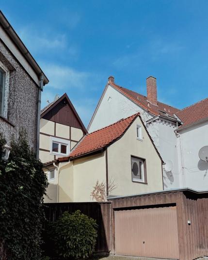 Hinterhofszene in Wiedenbrück. Man sieht Häuser, Dächer, eine Garage und Büsche. Die Dächer bilden verschiedene Dreiecke.