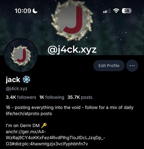 My Bluesky profile as of December 1st 2025 with 3.4k followers, 1k following, 35.7k posts. My profile picture is my regular black one, but with a blurred background of Christmas-styled trees, and a red knitted pattern within the “J”, with festive lights around it. The banner is a similar style, with text “@j4ck.xyz”.