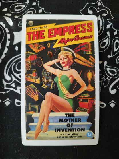 Card from the Sci Fi Tarot by Todd Alcott.
The Empress-III.
A vintage style science fiction poster depicting a woman in a one piece bathing suit and a sash, like a beauty contestant. She has a round glass helmet on the head, surrounded by various inventions for she is The Mother of Invention.