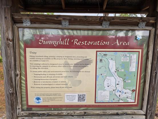 An information plate at an outdoors area that tells the name, "Sunny Hills Restoration Area", and has a map of the local environs as well as rules of use.