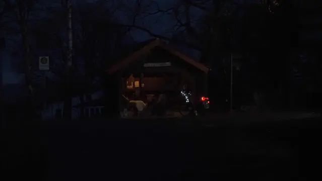 beleuchtete Bushaltestelle im dunkeln. Buntes Fahrrad davor. Im Wartehäusche befindet sich eine Krippe mit fast lebensgroßen Figuren