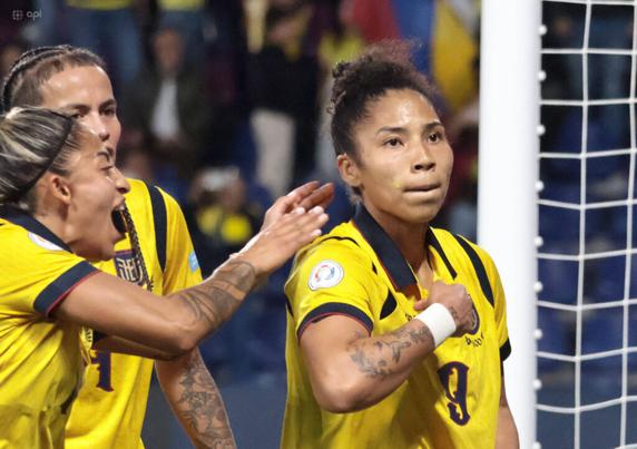 Nayley Bolaños jubelt neben dem Torpfosten mit entschlossenem Blick und zeigt sich selbst auf ihr Herz. Ihre Mitspielerinnen kommen jubelnd angelaufen.