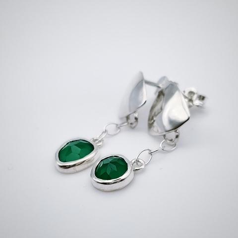 a pair of silver earrings with a green gemstone each. they have a silver triangle and from there is connected with a small silver chain the gemstone. there are in white background