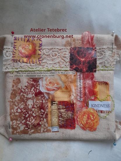 Abstract collage with fabric scraps, lace, and paper on beige fabric. The colours are mostly beige, orange, and some brown shades. Some paper is glued, some is stitched with coloured thread. Some words are visible like kindness and harmony.
